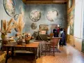 Interno del museo Palazzo Fortuny con opere d'arte alle pareti, arredi d'epoca e visitatori.