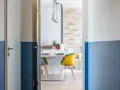 Peinture bicolore sur les murs d'un couloir et de portes, ouvrant sur une salle à manger moderne avec des chaises colorées.