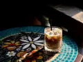 Orzeźwiający cold brew latte z lodem, podany na kolorowym, mozaikowym stoliku, w promieniach słońca.