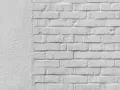 Mur blanc texturé à gauche, briques blanches à droite. Idéal pour un devis de prix piquage et rejointoiement.