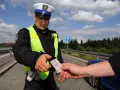 Policjant w kamizelce odblaskowej prosi o okazanie dokumentów. Czy trzeba mieć przy sobie prawo jazdy? Tak, podczas kontroli drogowej.