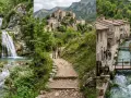Cascate del Menotre: un sentiero panoramico porta a cascate spettacolari e a un borgo medievale con un ruscello che scorre tra le case.