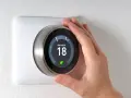 Una mano regola il termostato per impostare la temperatura desiderata, mostrando a cosa serve il termostato: controllare il riscaldamento per il comfort.