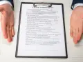 Dłonie wyciągnięte nad dokumentem "Lease Agreement" i długopisem.