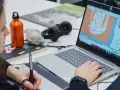 Studentka na studiach grafika Warszawa tworzy projekt na laptopie, używając tabletu graficznego.