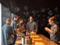 Une série de photos montrant une équipe en cuisine, devant un mur noir décoré de dessins scientifiques et floraux.