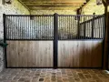 Plan d'un box cheval avec portes en bois et barreaux noirs.