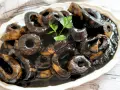 Calamares en su tinta, un plato tradicional español, servido en una fuente blanca con perejil fresco.