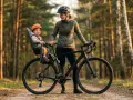 Szczęśliwe dziecko w foteliku rowerowym na tle lasu. To idealny wybór dla rodziców, którzy szukają najlepszego fotelik rowerowy ranking.