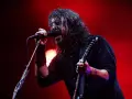 Dave Grohl z Foo Fighters na koncercie, śpiewający do mikrofonu i grający na gitarze.