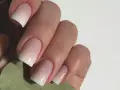 Mano con unghie curate e un effetto sfumato bianco e rosa, un esempio di nail art semplici ed eleganti.