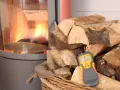 Poêle avec feu, bois de chauffage et humidimètre affichant 6.8%.