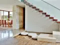 Escalera de madera flotante con barandilla de cristal. Ideas para decorar una escalera de madera con un estanque de guijarros y piedras.