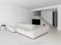 Soggiorno minimalista con divano modulare bianco e pavimento in resina lucida. Scale moderne integrano la TV.