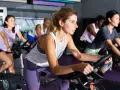 Women in a gym class experience the hiit cycling benefits, pedaling intensely on stationary bikes.