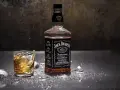 Butelka Jack Daniel's i szklanka z whisky, w której widać plusk. To klasyczny, old fashioned przepis na drinka.