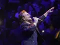Bono z U2 śpiewa na koncercie, zapowiadając u2 nowa płyta. Tłum w ciemnościach reaguje na jego występ.