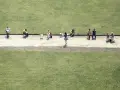 Luigi Ghirri uchwycił ludzi siedzących na krzesłach na tle zielonej trawy.