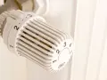 Vit termostat på ett element, redo att byta för att reglera värmen.