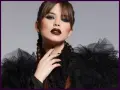Donna con trucco halloween semplice: labbra scure, occhi smokey blu e trecce. Abito nero con ruches.