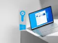 Grafika klucza z symbolem Windows i otwarty laptop z systemem Windows 11.
