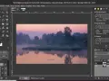 Mglisty poranek nad rzeką, edytowany w **GIMP 2.10**. Widać odbicie drzew w wodzie i wschód słońca.