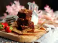 Saftige brownies rezept: Ein Stapel Schokoladenkuchen mit Nüssen, garniert mit frischen Erdbeeren und einem Krug Milch.