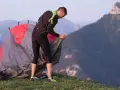 Un homme monte une tente sur une montagne. C'est ça, le bivouac : dormir à la belle étoile, loin de tout.