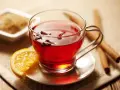 Té rojo con clavo y naranja, ideal para disfrutar de sus propiedades. Azúcar y canela al lado.