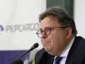 Mężczyzna w okularach przed mikrofonem na tle logo PKP Cargo.