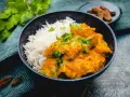 Cremiges Chicken Korma mit Basmatireis, garniert mit frischem Koriander. Ein köstliches indisches Gericht.