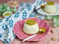 Delizioso semifreddo al pistacchio, guarnito con crema e granella di pistacchi, servito su un piatto rosa.