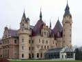 Imponujące pałace w Polsce, jak ten z kamienia i czerwonym dachem, zachwycają wieżami i bogactwem detali architektonicznych.