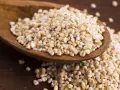 Kasza jęczmienna na drewnianej łyżce. Czy kasza jęczmienna ma gluten? Tak, jęczmień zawiera gluten.