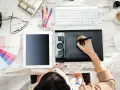 Kreatywna osoba pracuje przy biurku, tworząc projekty graficzne. To inspiracja, jak zarabiać w internecie, łącząc pasję z pracą.