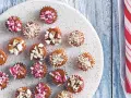 Små karameller med hackade nötter och polkagrisströssel, perfekta för julbak med barn. En rödvit polkagris ligger bredvid.