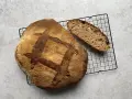 Chleb pszenno orkiszowy, świeżo upieczony, z chrupiącą skórką i puszystym wnętrzem, czeka na kromkę.