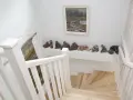 Klatka schodowa inspiracje: białe balustrady, drewniane stopnie i galeria ceramicznych rzeźb na półce.