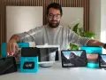 Mann präsentiert verschiedene Echo Show Generationen. Mehrere Geräte und Verpackungen sind auf dem Tisch zu sehen.