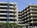 Edificio en construcción con grúa azul. La obra avanza lentamente, generando preocupación por sentencias de retraso en la entrega de vivienda de obra nueva.