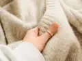 Mięciutki, beżowy, sfilcowany sweter z wełny, który otula dłoń.