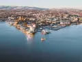 Widok na zimowe Oslo z wody. Mała łódka płynie po spokojnym akwenie, w tle rozciąga się miasto i ośnieżone wzgórza.