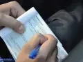 Ręka pisze mandat karny. Kierowca otrzymał mandat za brak przeglądu technicznego pojazdu.