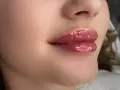 Błyszczące, pełne usta z efektem baby doll lips, podkreślone błyszczykiem.