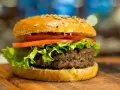 Apetyczny hamburger z sezamem, sałatą i pomidorem na desce.