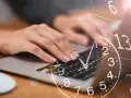 Dłonie piszą na klawiaturze laptopa, a nad nimi unosi się zegar. 13:31 znaczenie - czas na działanie, by osiągnąć cel.