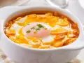 Sopa castellana en cuenco blanco con huevo escalfado y picatostes.