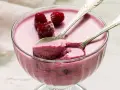 Himbeere-rotweincreme selbstgemacht in einer Glasschale, garniert mit frischen Himbeeren und zwei Löffeln.