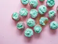 Urocze muffinki czekoladowe z miętowym kremem i kolorową posypką. Jedna babeczka z nadzieniem jest nadgryziona.