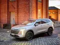 Srebrny Haval SUV zaparkowany na brukowanym dziedzińcu przed ceglanym budynkiem.